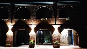 A building with a brick facade, multiple arches, and potted plants. - Relais Galatea (Montecorvino Pugliano)