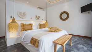 A modern bedroom with a large bed, bedside lamps, and a mounted TV. - Villa Karina (Tabanan)