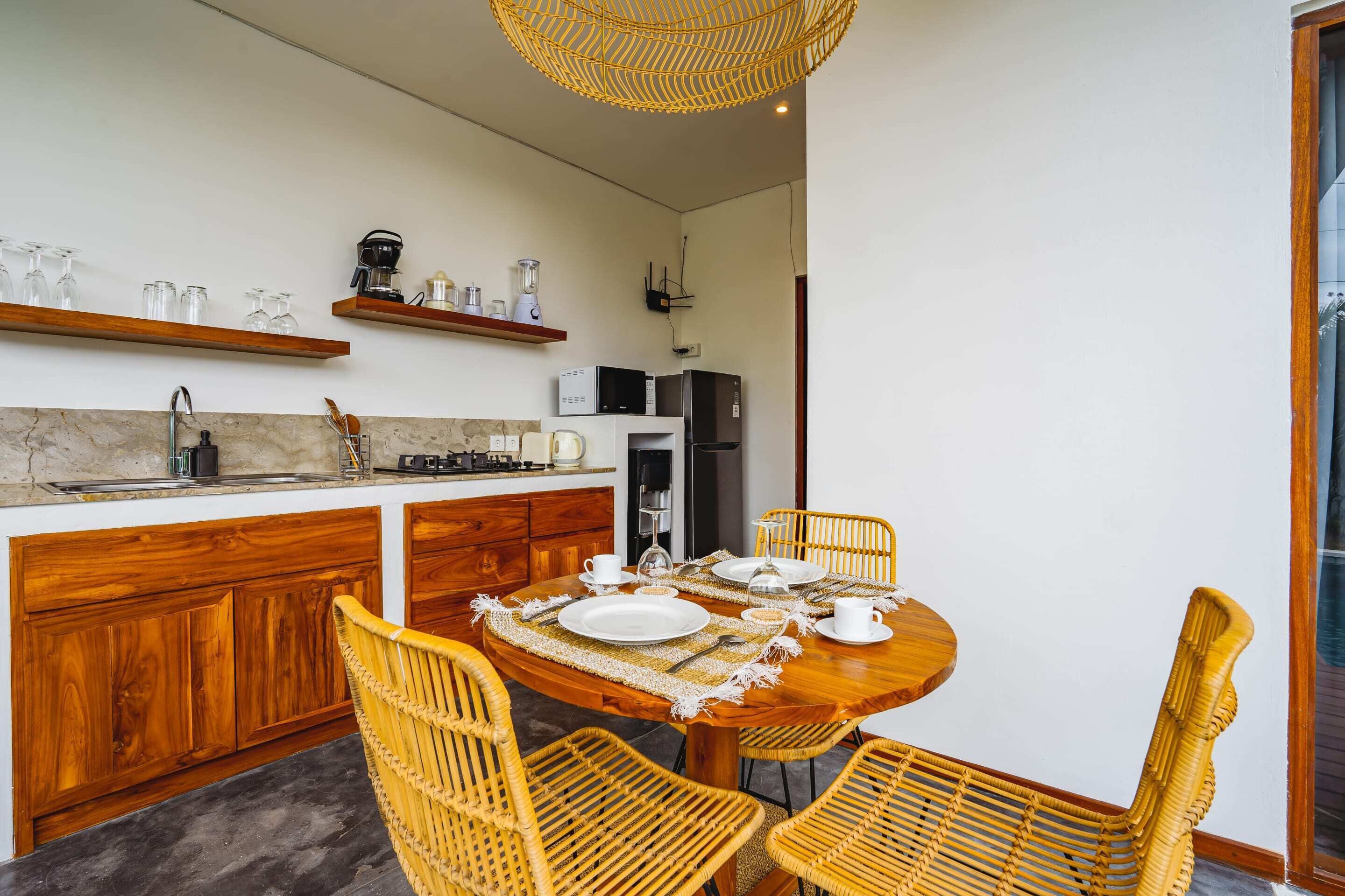 A modern kitchen with wooden cabinets, a dining table set for four, and a hanging light fixture.
