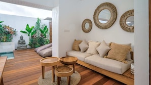Ein modernes Wohnzimmer mit Holzboden, einem beigefarbenen Sofa und drei runden Spiegeln an der Wand.