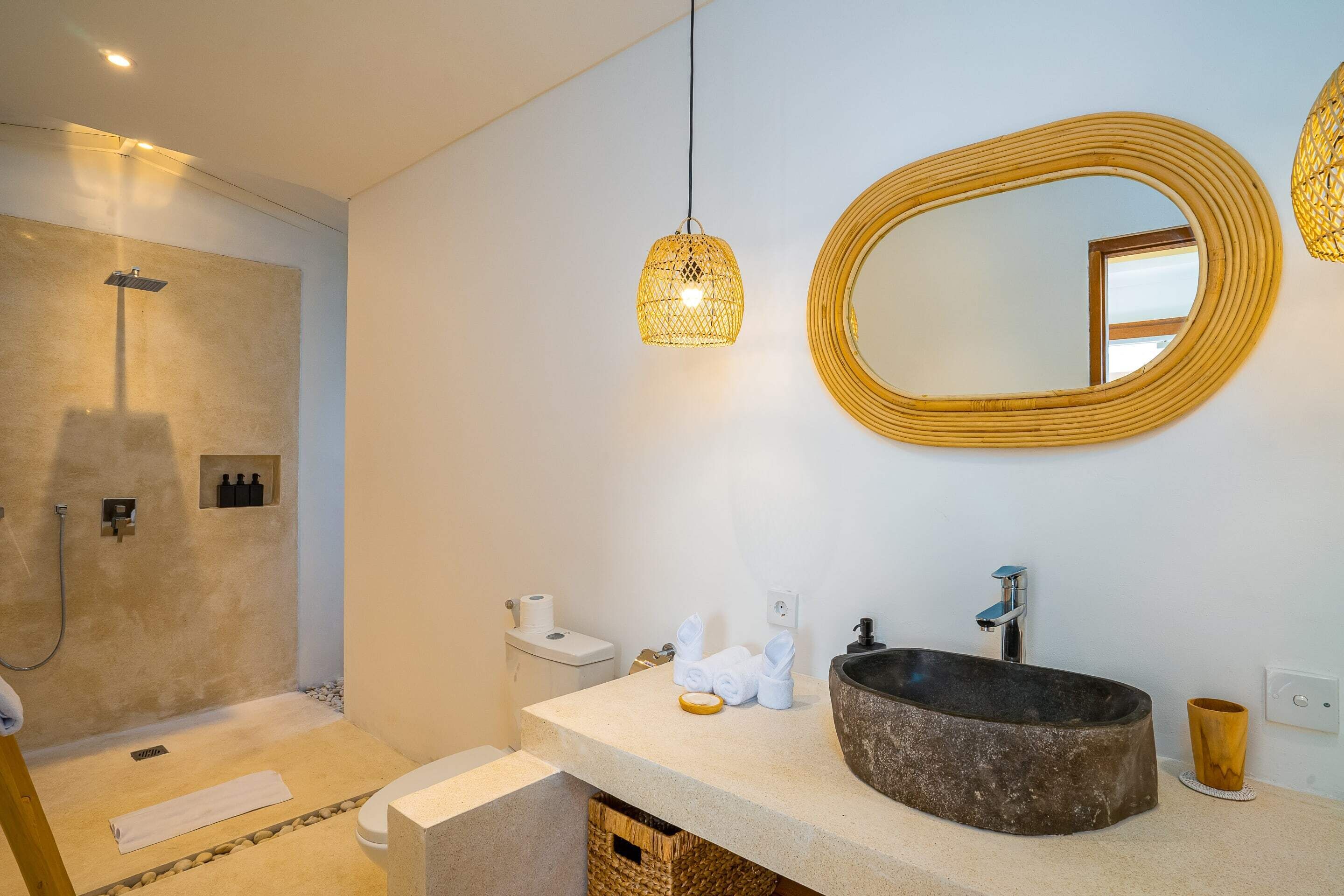 A bathroom with a large round mirror, a vessel sink, and a shower area.