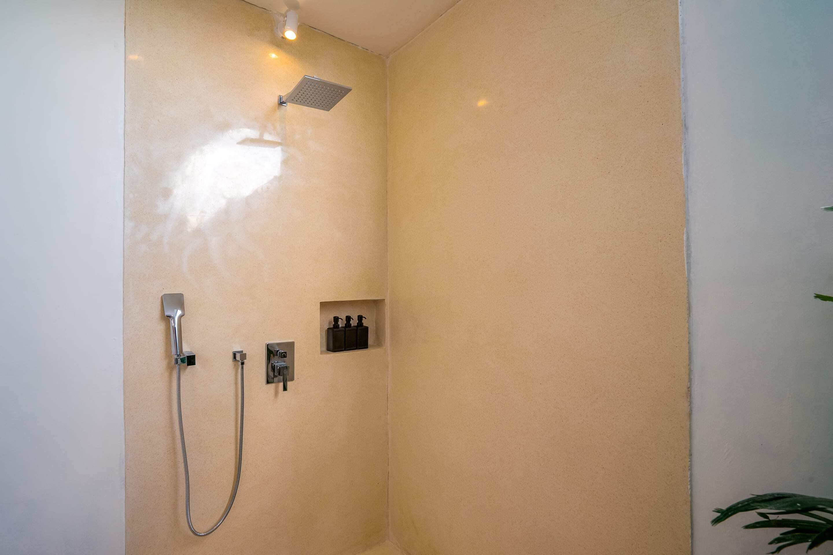 Une douche équipée d’un pommeau de douche à main, d’un robinet mural et d’un panneau de commande.