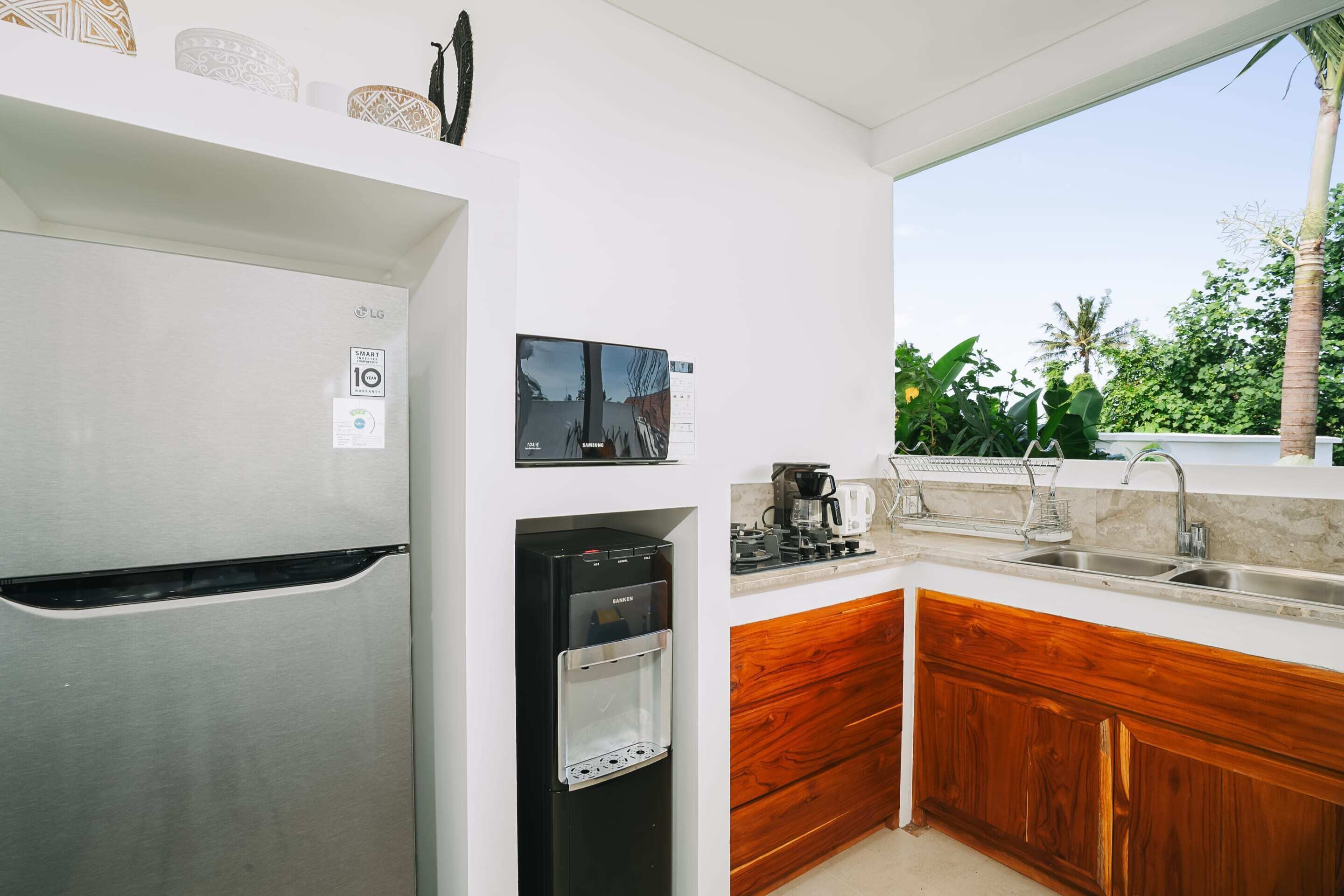 A modern kitchen with a stainless steel refrigerator, a built-in water dispenser, a coffee maker, and a sink.