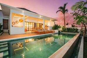 A modern house with a swimming pool, wooden deck, and outdoor seating area. - Villa L at Seseh (Munggu)