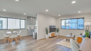 Ein modernes Wohnzimmer mit Essbereich, Küche und großen Fenstern.