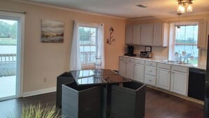 A kitchen with a central island, white cabinets, and a view of the outdoors. - Carrick Bend -Balcony View of ICW- Dog Friendly! (Coinjock)