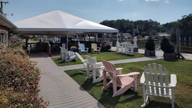 A covered outdoor area with a tent, white Adirondack chairs, and a wooden deck. - Carrick Bend -Balcony View of ICW- Dog Friendly! (Coinjock)