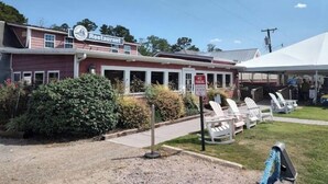 A restaurant with a red exterior, a signboard, and outdoor seating with white chairs. - Carrick Bend -Balcony View of ICW- Dog Friendly! (Coinjock)