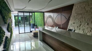 Experience the sleek, modern reception area with a glass reception desk and a living green wall.