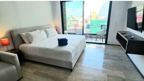 Relax in a spacious room with a large bed, flat-screen TV, and sliding glass door leading to a city view.