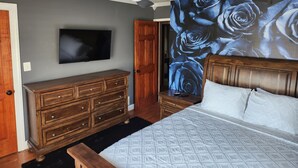 A bedroom with a bed, wooden dresser, ceiling fan, TV, and a wall with a blue rose mural. - 3bd Family-sized house, 5 minutes to National park, 12 minutes to the Capital. (Washington)