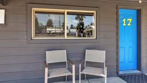 A house with a blue door marked with the number 17, two white chairs outside, and a window above the door. - Stay at Lazy Duck Inn #17 Double Queens, just 1 minute from Yellowstone in West Yellowstone. (West Yellowstone)