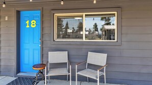 A blue door with the number 18, two chairs, and a small table outside a building with a window. - Relax at Lazy Duck Inn #18: a 2BR suite with kitchenette, just 1 minute to Yellowstone. (West Yellowstone)