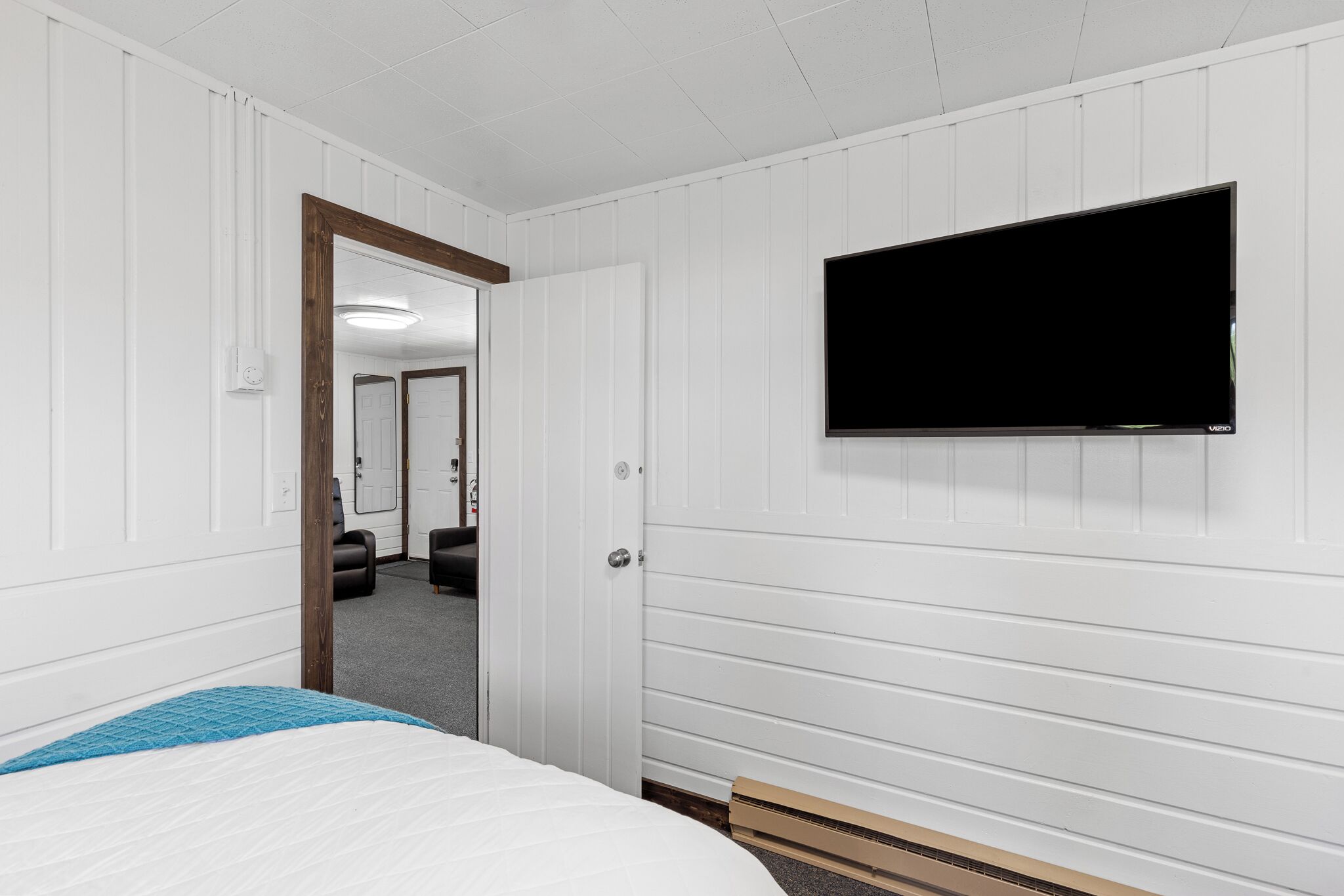 A hotel room with a bed, a TV mounted on the wall, and a door leading to another room.