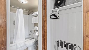 A bathroom with a white bathtub, a white toilet, a shower curtain, a towel rack, and a ceiling fan. - Stay at Lazy Duck Inn #20 Double Queens, just 1 minute to Yellowstone! (West Yellowstone)