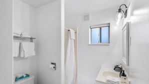A bathroom with a shower, a toilet, a sink with a mirror, and a window. - Cozy Lazy Duck Inn #22: 1 min to Yellowstone, 2 full beds, kitchen, sleeps 4! (West Yellowstone)