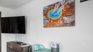 Una sala conferenze con un armadietto in legno, sedie color acquamarina, un tavolo e un quadro che raffigura una piscina geotermica.