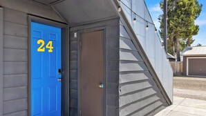 A building with a blue door marked with the number 24, a small porch area, and a sloped roof. - Cozy King Suite at Lazy Duck Inn, just 1 minute from Yellowstone! #24 (West Yellowstone)