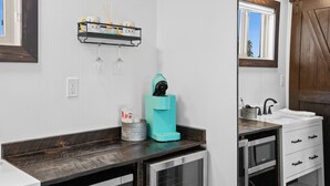 A modern kitchen with a dark countertop, a built-in dishwasher, and a window with a view of the outdoors. - Discover the Lazy Duck Inn #26 King Suite, just 1 minute from Yellowstone! (West Yellowstone)