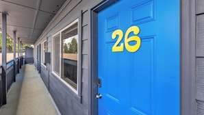 A blue door with the number 26, a covered walkway, and windows along the side. - Discover the Lazy Duck Inn #26 King Suite, just 1 minute from Yellowstone! (West Yellowstone)