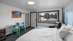 Ein Schlafzimmer mit Bett, Schreibtisch, Stuhl, Fenster mit Blick und einem Bild an der Wand.