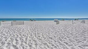 Una extensa playa de arena con cielo azul despejado y mar tranquilo.
