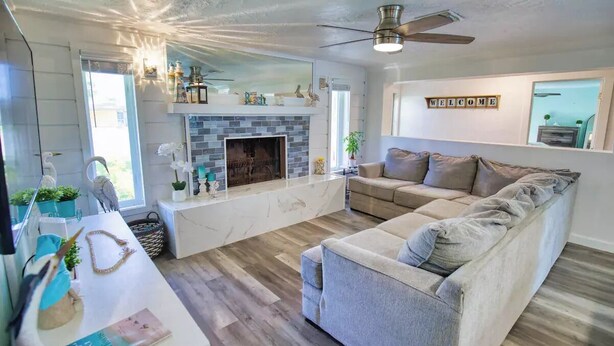 Un salon avec une cheminée, un canapé et un ventilateur de plafond.