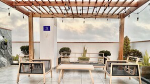 A covered outdoor seating area with wooden furniture and string lights. - Exclusive Panoramic Ocean View (1805) (Callao)