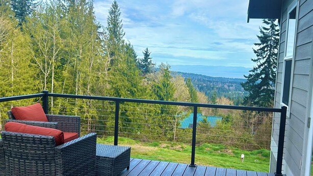 A balcony with wicker furniture and a view of a forest and mountains. - Wildcat Cottage  (Port Angeles)