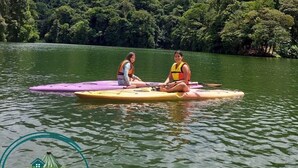 Two people on a paddleboard in a lake with a mountain in the background. - Hospedaje Peña del Arenal (La Fortuna)