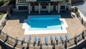 Een hotel met een zwembad, lounge stoelen en een terras van baksteen.