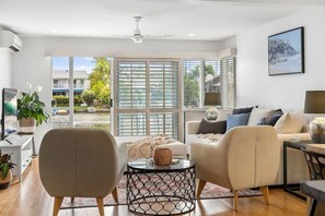 A modern living room with a sofa, two armchairs, a coffee table, and a television.