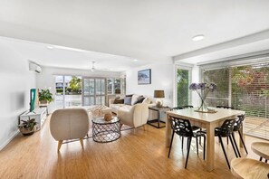 A modern living room with a sofa, coffee table, dining table, and chairs.