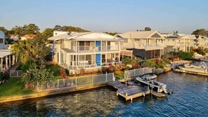 A waterfront residential area with modern houses, a dock, and a boat. - Sunsets at Snowmas Pooch Friendly Stunning Views (Noosa)