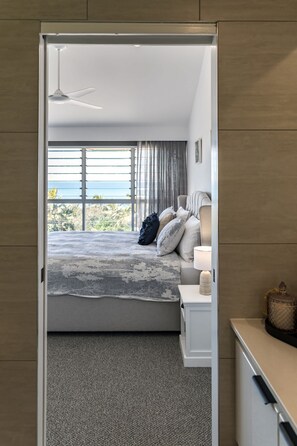 Une chambre à coucher avec un lit, une table de chevet, une lampe et une vue sur l’extérieur.