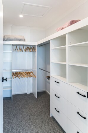 Um closet amplo com prateleiras abertas, espaço para pendurar roupas e gavetas.