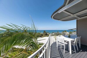 Un balcon avec une table et des chaises, offrant une vue sur la côte.