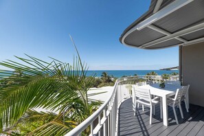 Terraza con mesa y sillas con vista a la playa y al océano.