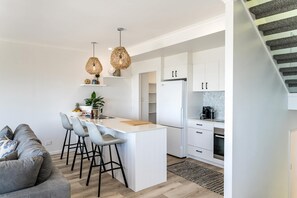 Cozinha moderna com armários brancos, uma ilha central e forno embutido.