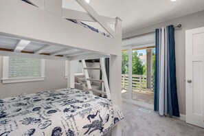 Un dormitorio con literas, un balcón con vistas y una puerta con cortinas.