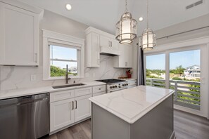 A modern kitchen with white cabinetry, a stainless steel dishwasher, a gas stove, and pendant lighting.