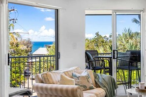 A balcony with a view of the ocean, a sofa, and a table with chairs. - 3 Andari Sunshine Beach Modern Apt 1 Min Beach (Noosa)
