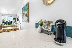 A modern reception area with a coffee machine, a framed artwork, and a seating area with a view.