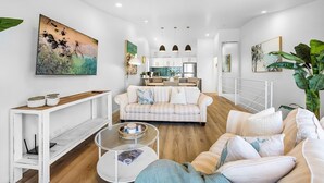 Una sala de estar moderna con sofá, una mesa de centro y un comedor, con una cocina al fondo.