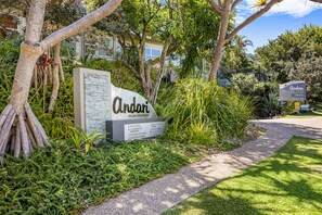 A sign for Andari Holiday Apartments with a list of amenities including security, parking, and on-site management.