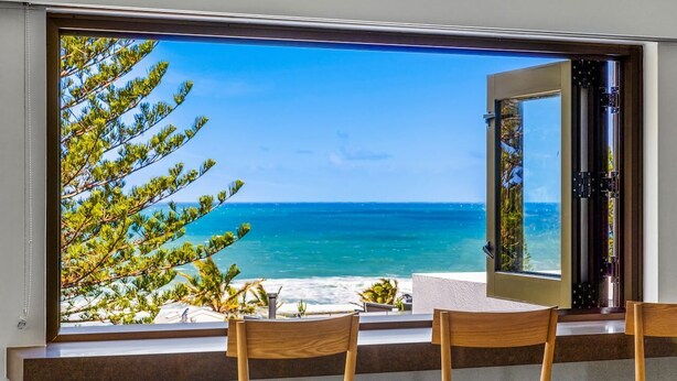 Un comedor con un ventanal grande que da a una playa y al océano.