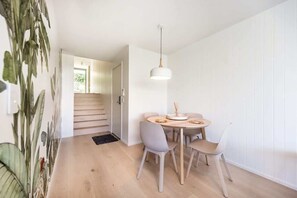 A modern dining area with a round table, four chairs, and a pendant light.