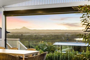 A balcony with a view of a mountain range and a cityscape.