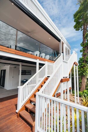 A modern house with a wooden deck, white railings, and large windows.