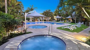 A pool area with a hot tub, lounge chairs, and umbrellas. - Beautiful Apt in Luxe Beachside Noosa Resort (Noosa)